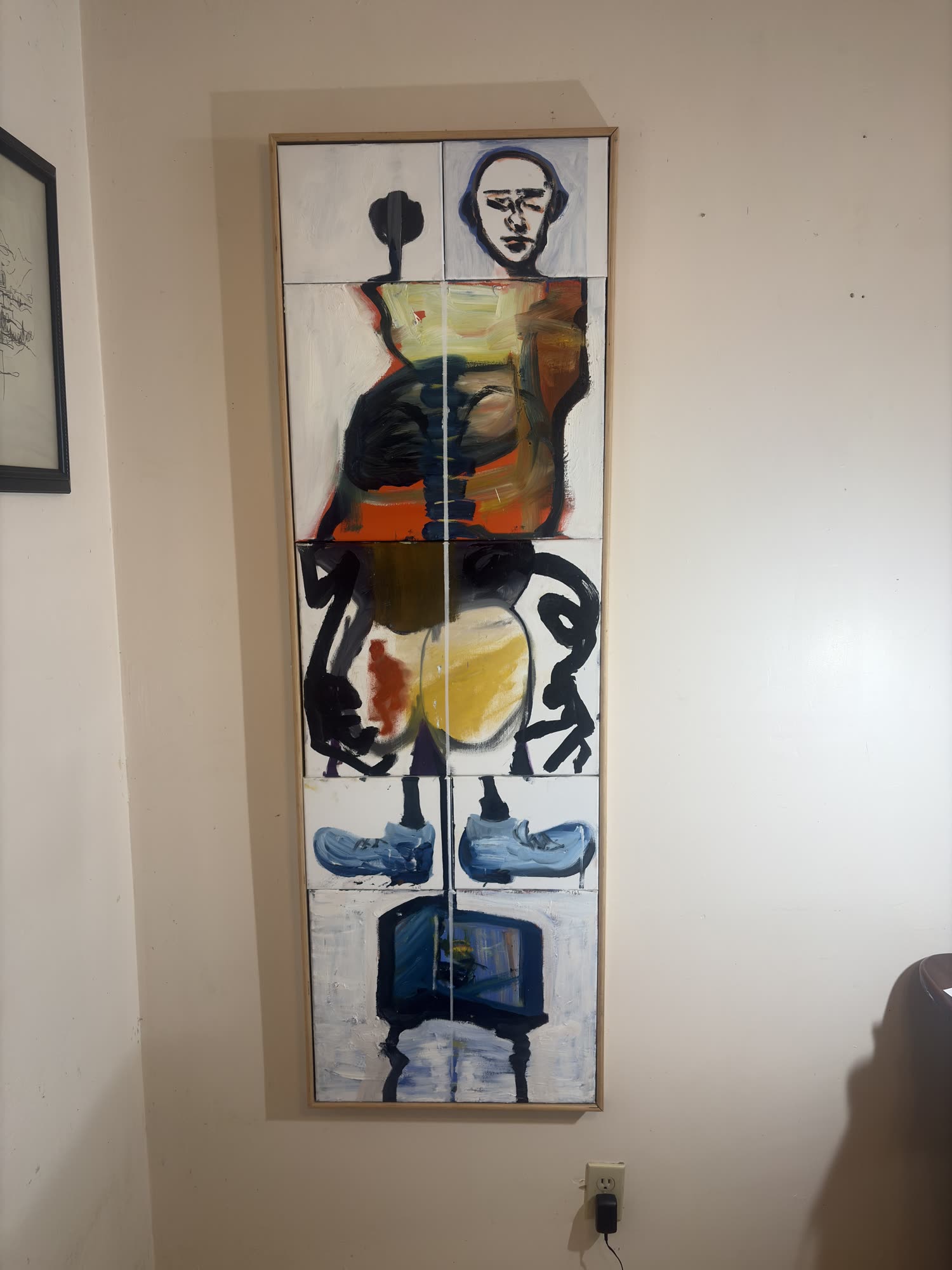 The ten-panel figure painting hanging in a pale wooden frame on the studio wall, an electrical outlet below it.