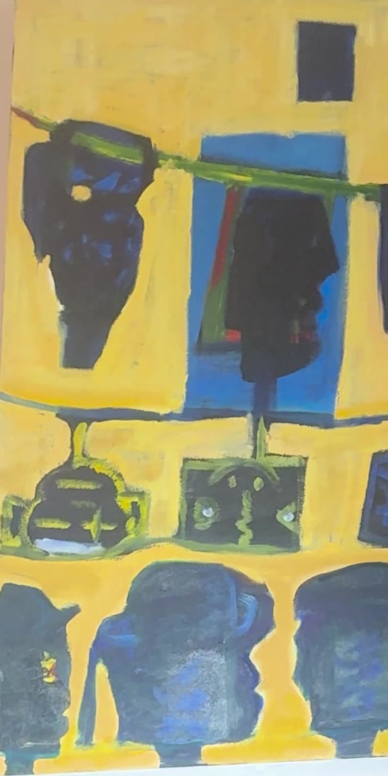 Yellow painting with dark blue heads and profile silhouettes arranged in rows, seen at an angle in the studio.